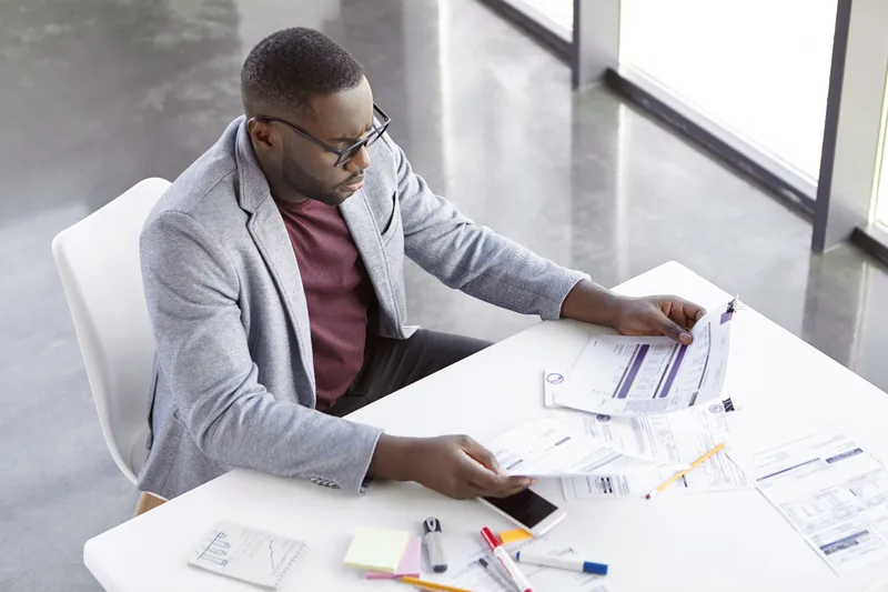 Property owner reviewing project records at a desk by large office windows.