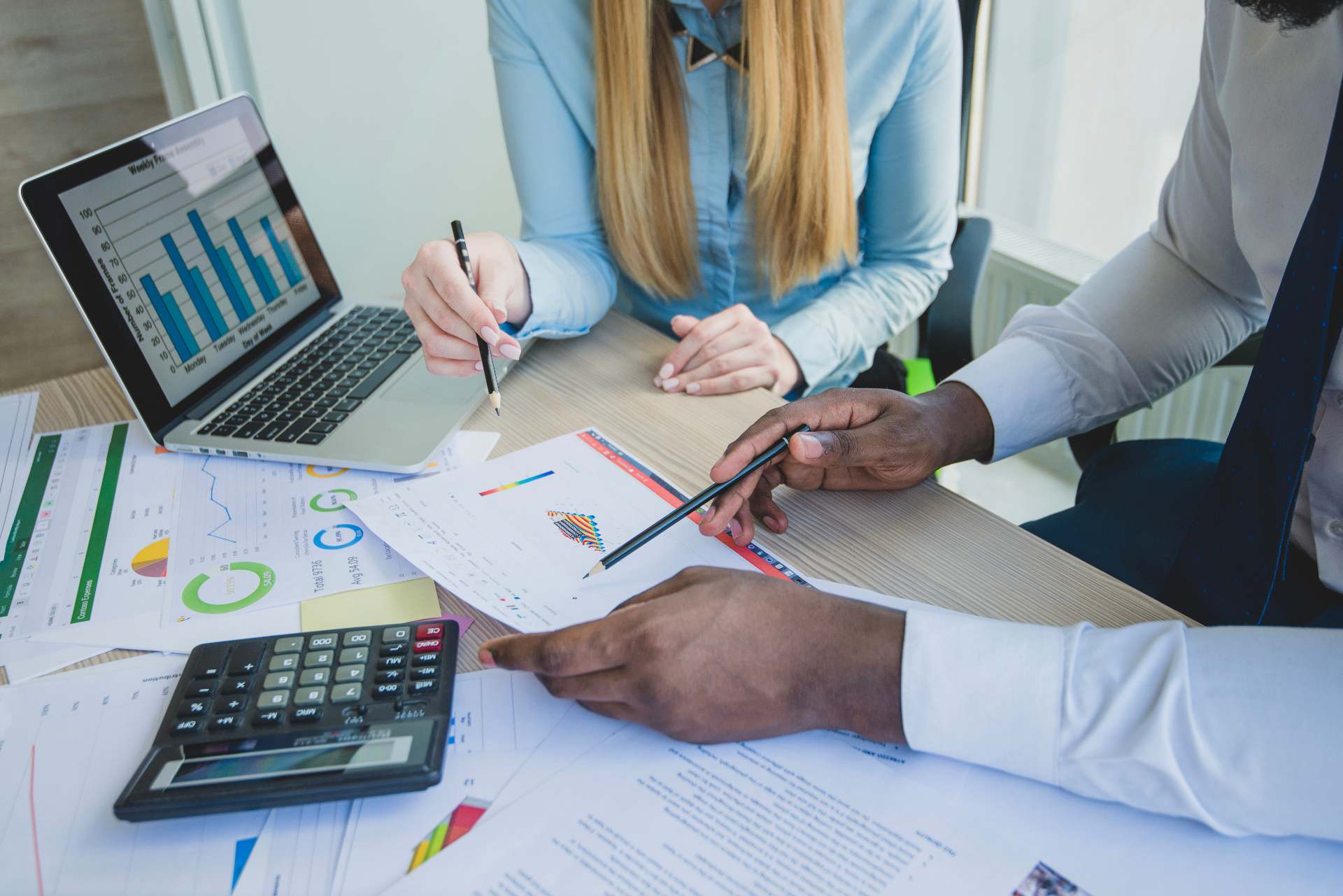 Colleagues reviewing charts and financial reports together at a desk.